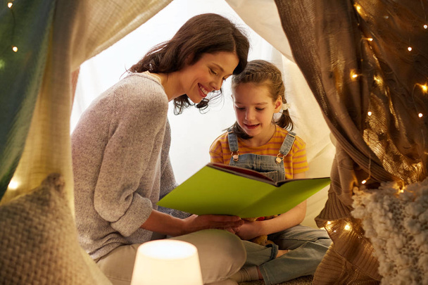 happy family reading book in kids tent at home - Foto, Imagen