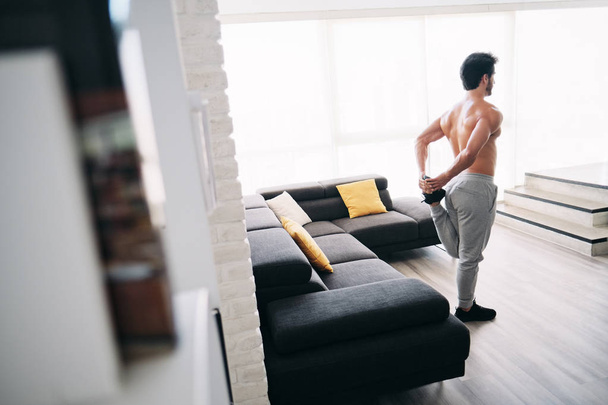 Hombre adulto Entrenamiento de fitness en casa Estirar los músculos antes del entrenamiento
 - Foto, imagen