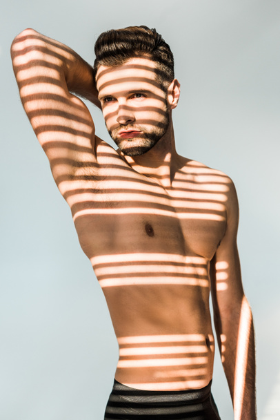 handsome seductive man with shadows on muscular torso isolated on grey - Fotoğraf, Görsel