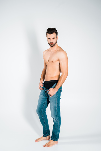 handsome bearded man in jeans posing on grey - Photo, Image