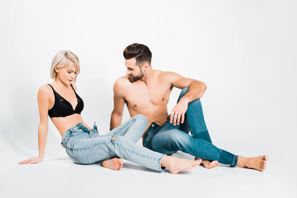 handsome man and beautiful woman posing in underwear and jeans on grey - Foto, Imagen