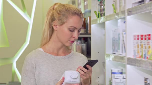 Женщина с помощью смартфона, просмотр информации в Интернете во время покупки лекарств
 - Кадры, видео