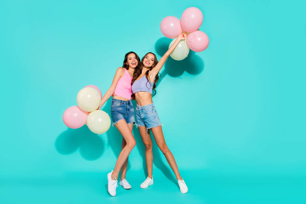 Full length body size photo funny beautiful amazing two she her ladies colored balloons hands arms mood beach party wearing shiny jeans denim shorts tank tops isolated teal bright vivid background - Foto, immagini