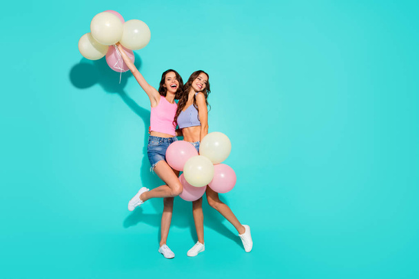 Full length body size photo funny beautiful amazing two she her ladies colored balloons hands arms raised skinny legs wearing shiny jeans denim shorts tank tops isolated teal bright vivid background - Foto, immagini