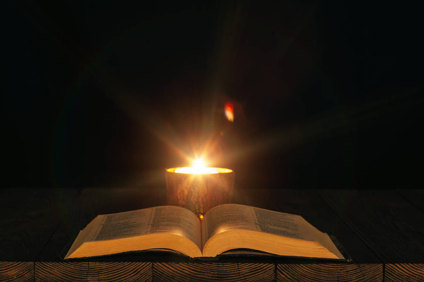 Raamattu pöydällä valossa kynttilän - Valokuva, kuva