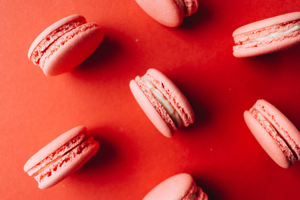 composition of delicious pink macaroons on red table sweet dessert  - Fotó, kép