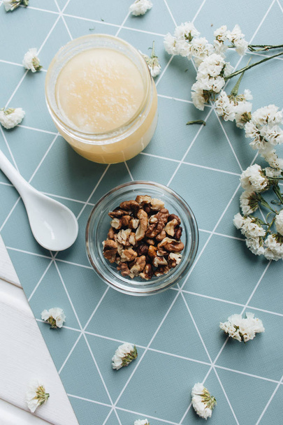 nueces, miel y flores blancas en la mesa
 - Foto, imagen