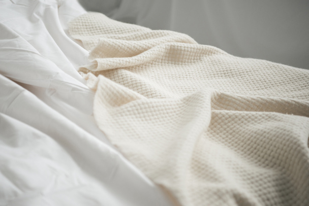 Primer plano de la acogedora cama vacía con manta blanca y sábanas
  - Foto, Imagen