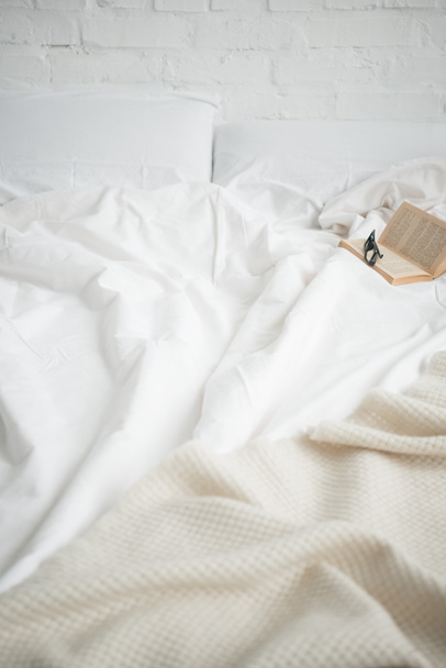 book and glasses on empty cozy white bed  - Zdjęcie, obraz