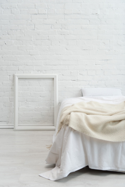 dormitorio con cama blanca vacía y marco de imagen
 - Foto, imagen
