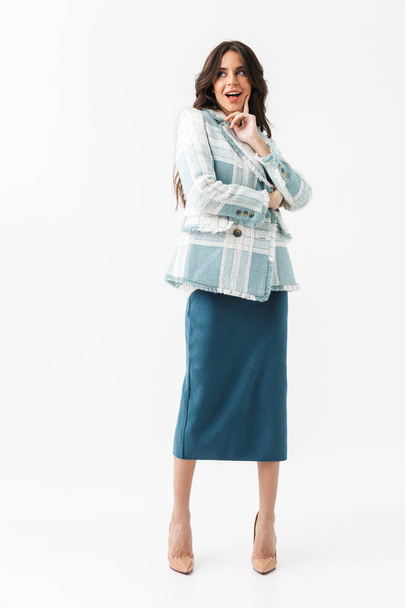 Full length portrait of a confident woman dressed in plaid jacket and skirt standing isolated over white background - Valokuva, kuva