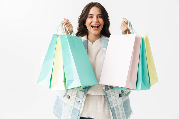 Veselá brunetka žena držící nákupní tašky izolované na bílém pozadí - Fotografie, Obrázek