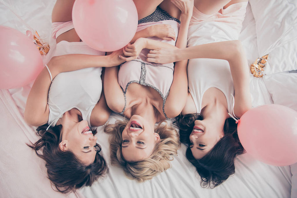 Top above high angle view of nice cute lovely attractive charming cheerful girlfriends having fun lying on bed day daydream dream pleasure in light white interior decorated house indoors - Фото, зображення