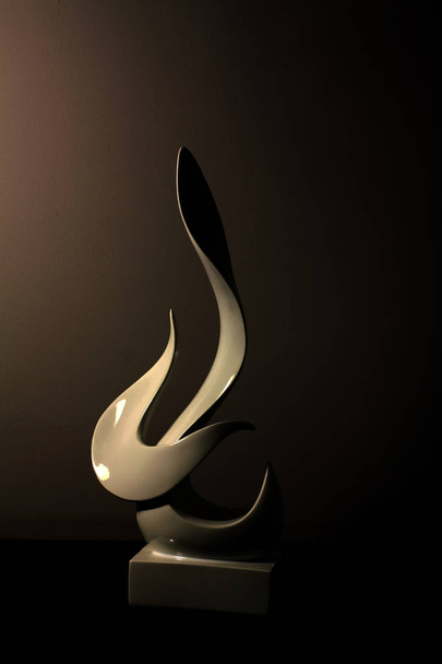 White abstract statuette on the table is reflected in a black mirror background - Photo, Image