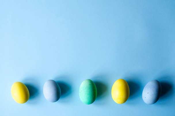 Multi-színes húsvéti tojást a kék háttér. Van egy hely, a szöveg. - Fotó, kép