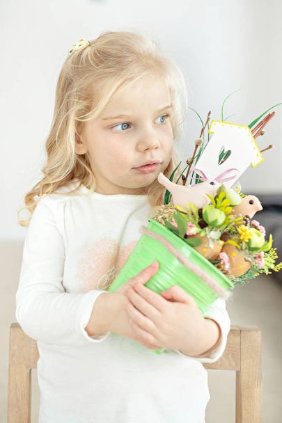 Το χαριτωμένο μικρό κορίτσι κάνοντας διακόσμηση για το Πάσχα. Πάσχα μπουκέτο, αυγά, Πάσχα, παραδόσεις. - Φωτογραφία, εικόνα