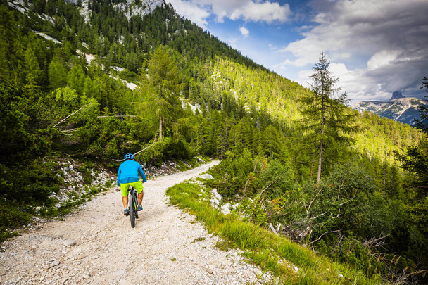 Ciclismo turístico em Cortina d 'Ampezzo, deslumbrantes montanhas rochosas ao fundo. Homem montando trilha de fluxo de enduro MTB. Província do Tirol do Sul da Itália, Dolomites
. - Foto, Imagem