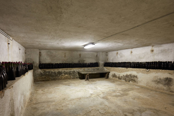 Bodrum şarap şişeleri ve eski ev iç ahşap masa - Fotoğraf, Görsel