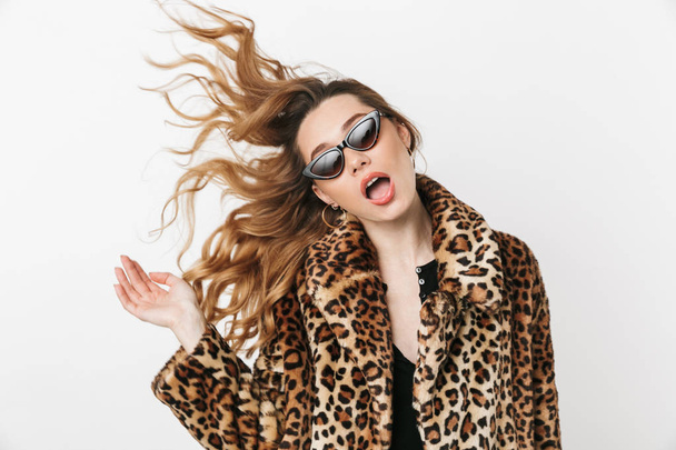 Beautiful young woman wearing leopard coat standing isolated over white background, posing - Foto, Imagem