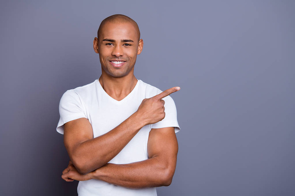 Close up photo attractive strong healthy masculine dark skin he him his macho bald head arm finger show way gift present sale discount wearing white t-shirt outfit clothes isolated grey background - Foto, Imagem