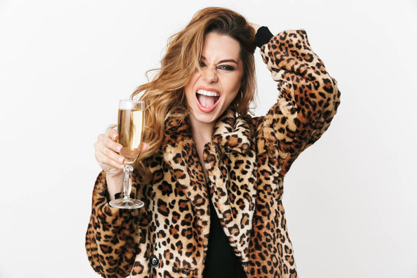 Beautiful young woman wearing leopard coat standing, holding glass with champagne - Foto, Bild
