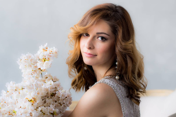 Portrait de belle jeune femme avec bouquet de sakura blanc dans les mains
 - Photo, image