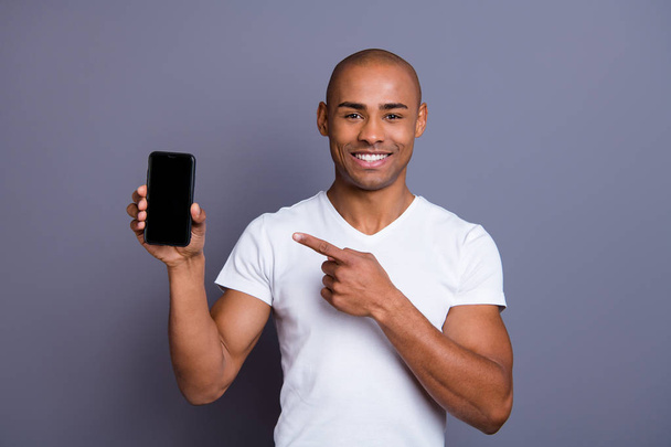 Close up photo strong healthy dark skin he him his macho bald head finger show new telephone version advising buy buyer promotional wearing white t-shirt outfit clothes isolated grey background - Foto, Imagen