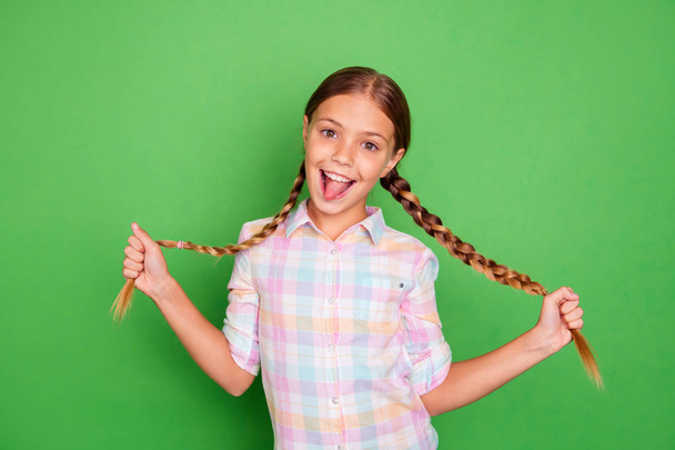 Close up photo small little age she her girl hold hand arm showing tails tongue out mouth positive optimistic pretty wear casual checkered plaid shirt isolated green bright vibrant vivid background - Fotografie, Obrázek