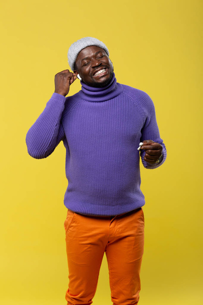 Joyful handsome dark-skinned model wearing modern earphones - Фото, изображение