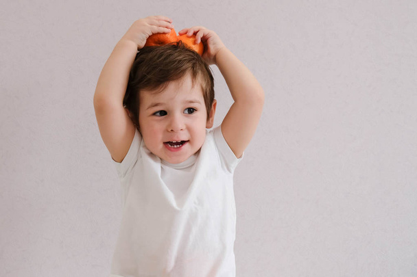 Bambino carino tiene mandarino, isolato su bianco
 - Foto, immagini