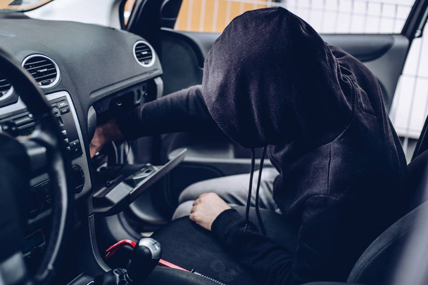 Ladrón enmascarado en un pasamontañas robando objetos de valor del coche
 - Foto, imagen