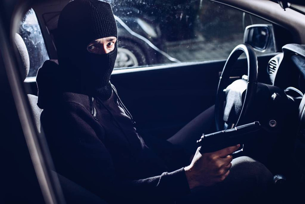 Maskierter Terrorist mit Pistole im Auto - Foto, Bild