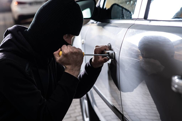 Κλέφτης αυτοκινήτων ανοίγοντας πόρτες του κλεμμένου αυτοκινήτου. Κλέφτης αυτοκινήτων, κλοπή αυτοκινήτου - Φωτογραφία, εικόνα