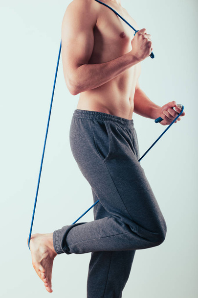 Young man holding skipping rope, doing exercises at home. Portrait orientation - Valokuva, kuva