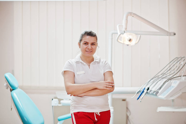 Női fogorvos nő portréja átlépte a fegyverek a fogorvosi rendelőben közelében szék állt. - Fotó, kép