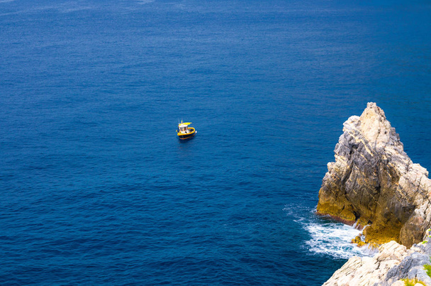 Yellow boat on blue dark water of Grotta di Lord Byron near coast with rock cliff, Portovenere town, Ligurian sea, Riviera di Levante, National park Cinque Terre, La Spezia, Liguria, Italy - Foto, Bild