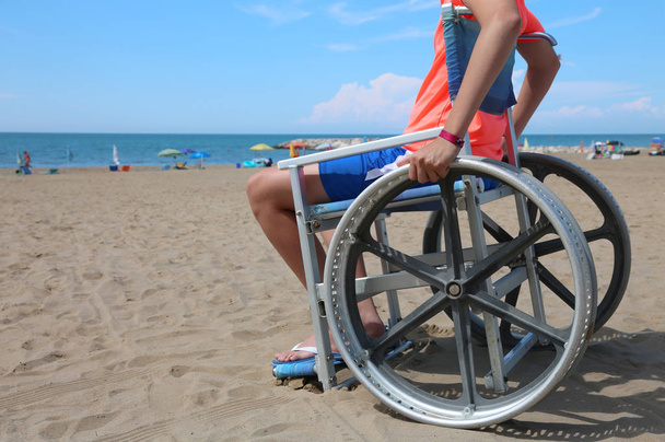 Pieni poika pyörätuolissa rannalla keinona kesällä
 - Valokuva, kuva