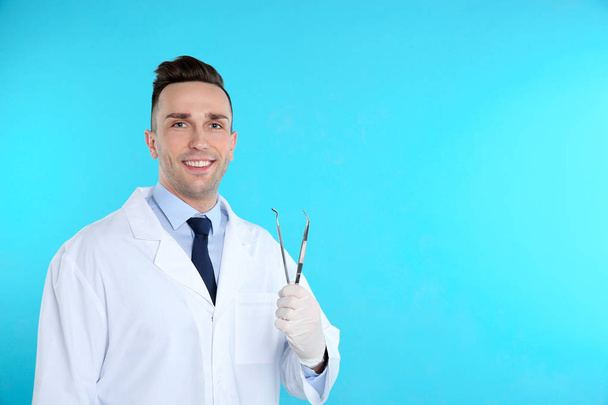 Male dentist holding professional tools on color background. Space for text - Foto, immagini