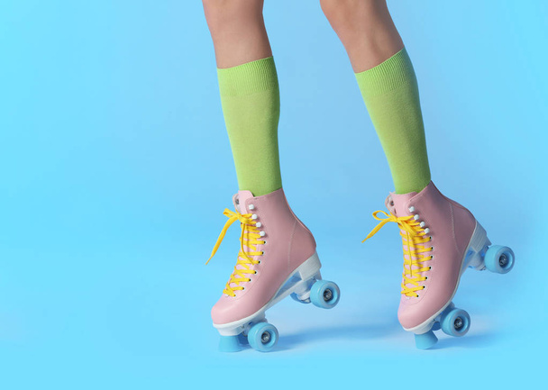 Woman with vintage roller skates on color background, closeup. Space for text - Фото, зображення