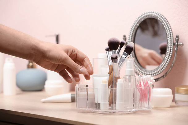 Woman taking cosmetic products from holder on dressing table, closeup - Foto, Imagen