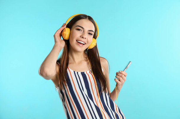 Beautiful young woman listening to music with headphones on color background - Valokuva, kuva