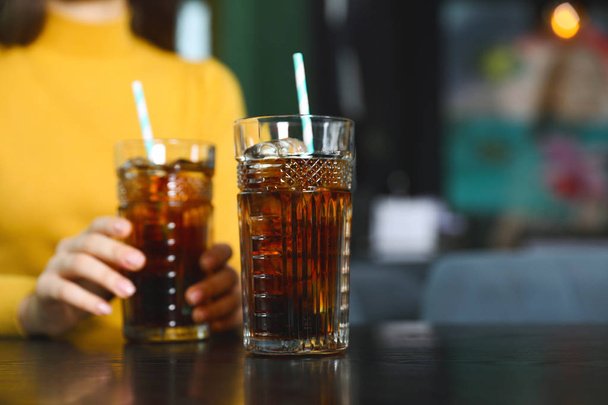Glass of refreshing cola and blurred woman on background. Space for text - Fotoğraf, Görsel