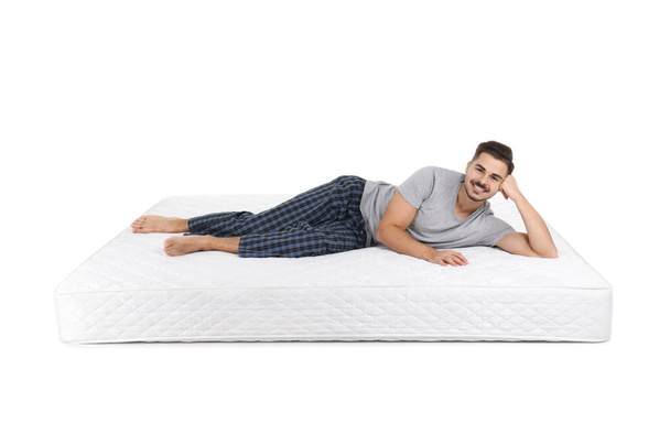 Young man lying on mattress against white background - Photo, image