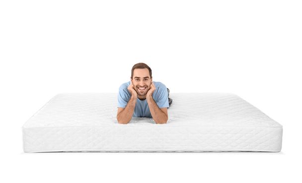 Young man lying on mattress against white background - Valokuva, kuva