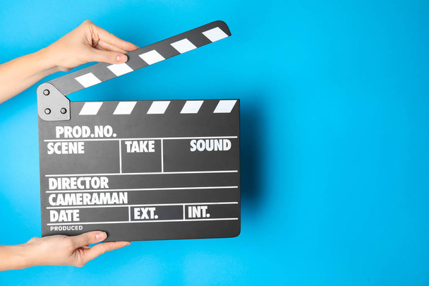 Woman holding clapperboard on color background, closeup with space for text. Cinema production - Foto, imagen