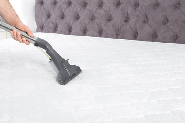 Man disinfecting mattress with vacuum cleaner, closeup. Space for text - Zdjęcie, obraz