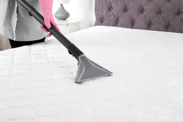 Woman disinfecting mattress with vacuum cleaner, closeup. Space for text - Valokuva, kuva