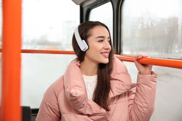 Beautiful young woman listening to music with headphones in public transport - Foto, Imagen