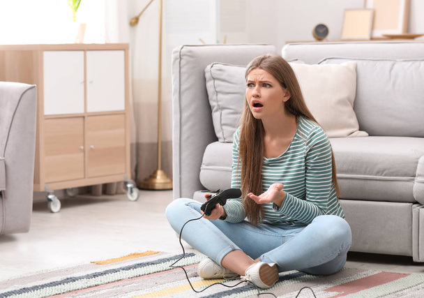 Emotional young woman playing video games at home - Photo, image