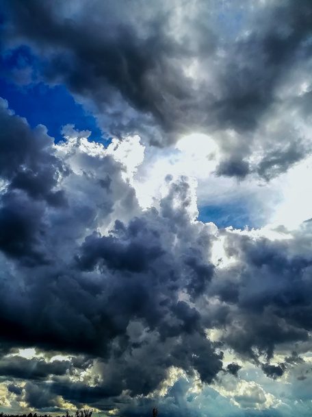 Ciel avec nuages orageux menaçants dans différentes tons bleus avec la lumière du soleil à travers
 - Photo, image